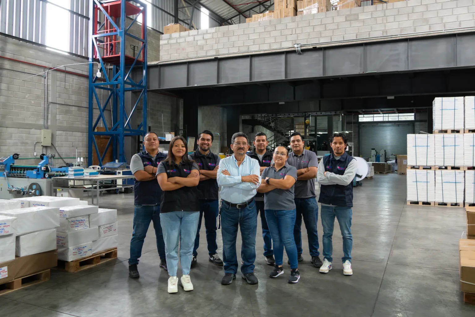 Bodega luminosa con altas pilas de papel sobre estibas de madera